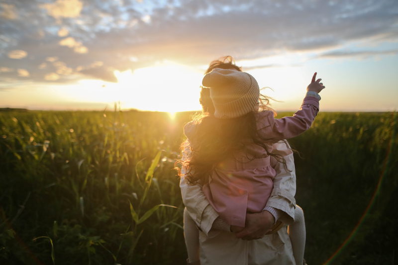 Parent tenant la main de son enfant en contre-jour