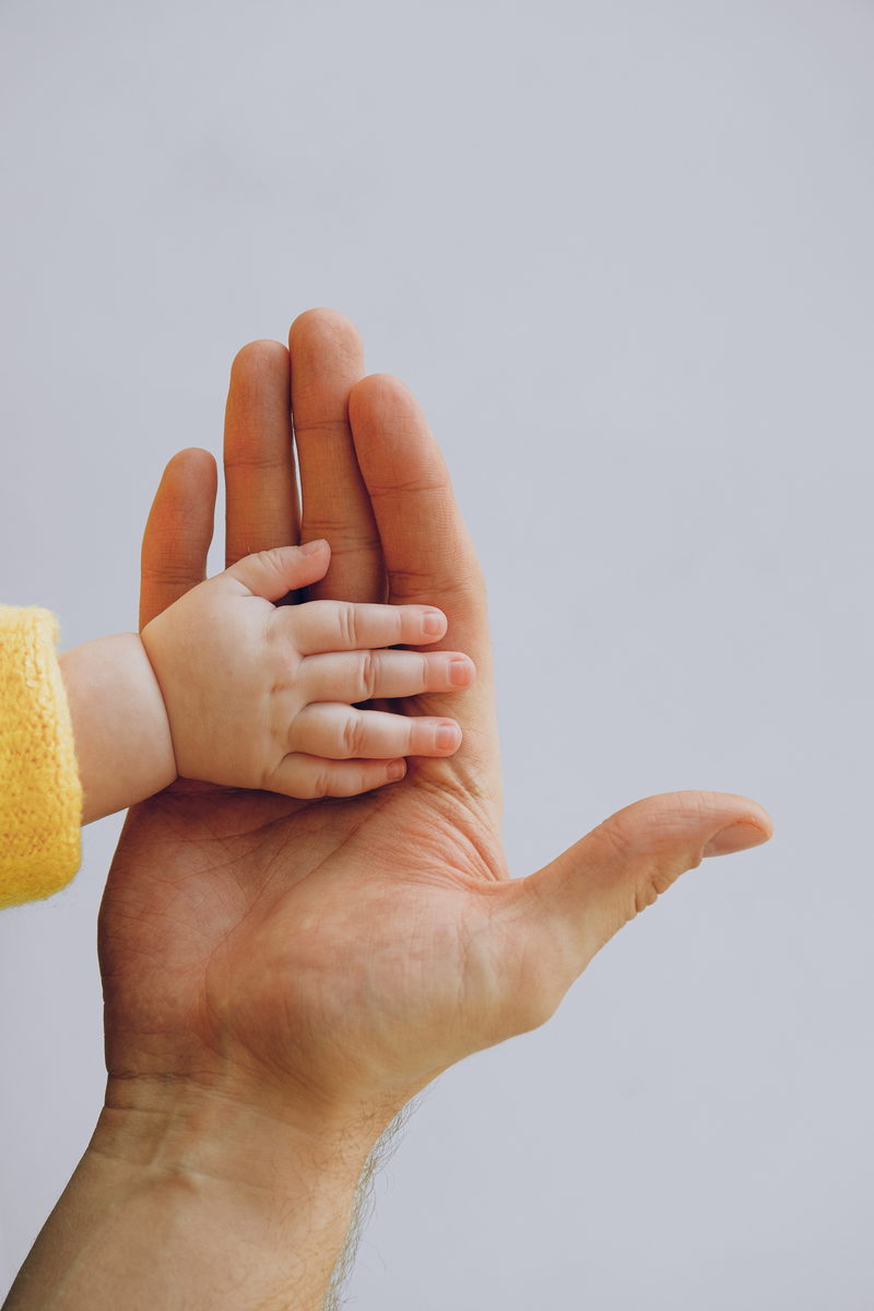Main d'un adulte tenant la main d'un tout-petit